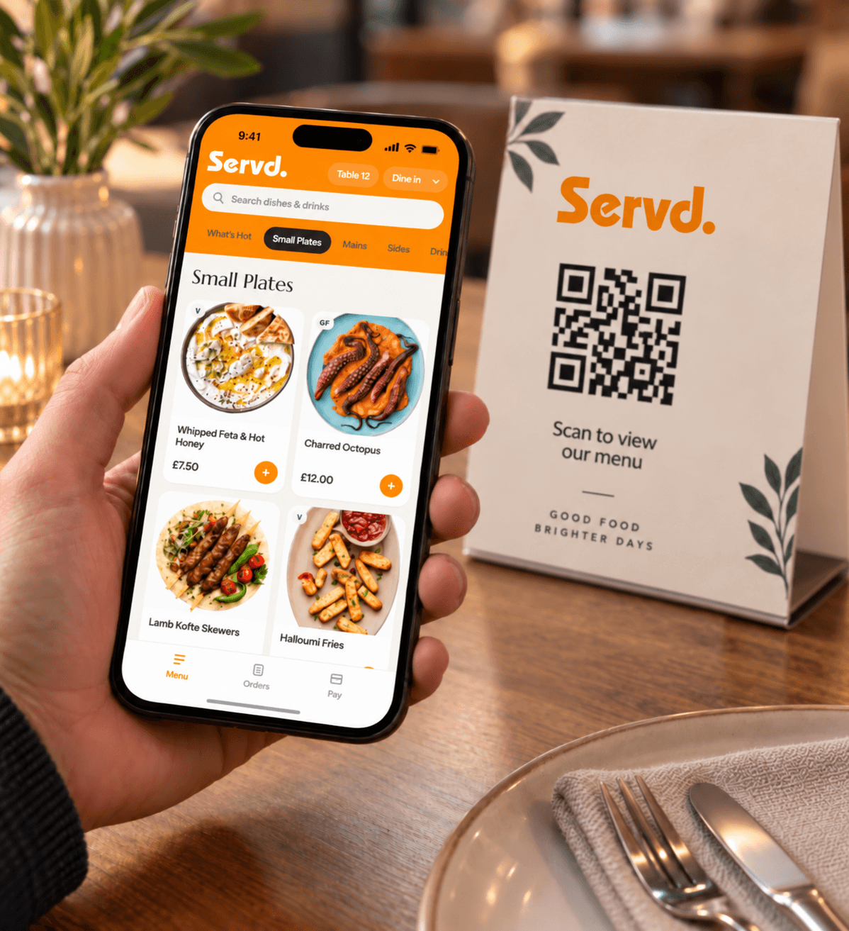 Guest holding a phone showing the Servd menu beside a table QR card